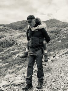 A Dad carrying his daughter down a mountain